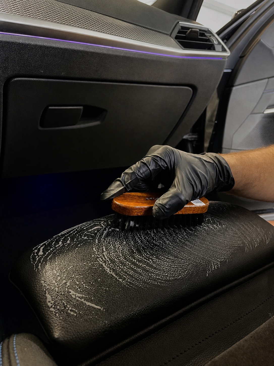 Handschuh und weiche Bürste bei der Reinigung einer Lederarmauflage