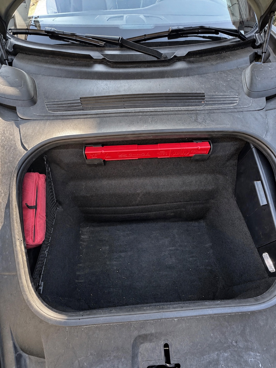 Vorderer Gepäckraum eines Porsche 911 vor der Reinigung mit sichtbarem Staub und losen Partikeln