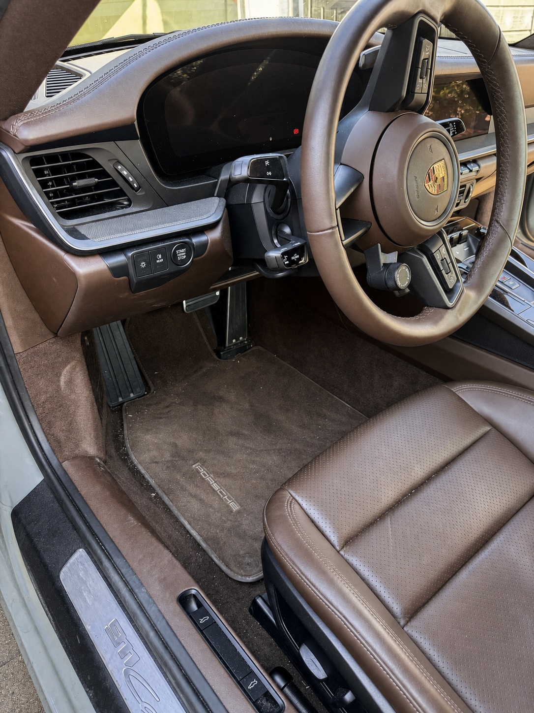 Fahrerplatz eines Porsche 911 vor der Detailreinigung mit verschmutzter Fußmatte